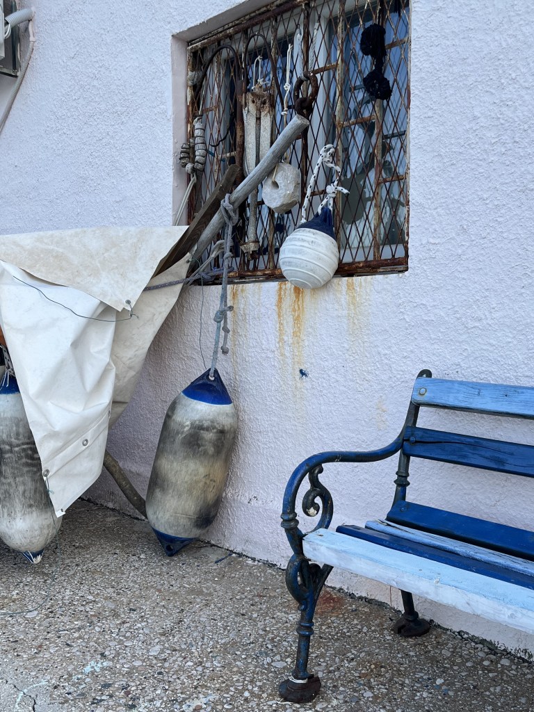 Banc bleu et bouée de pêcheur devant un mur blanc