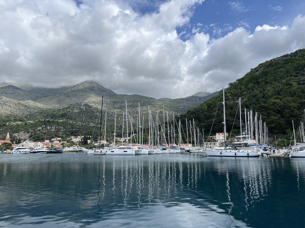 Marina en Croatie, avec des montagnes derriere et un ciel nuageux