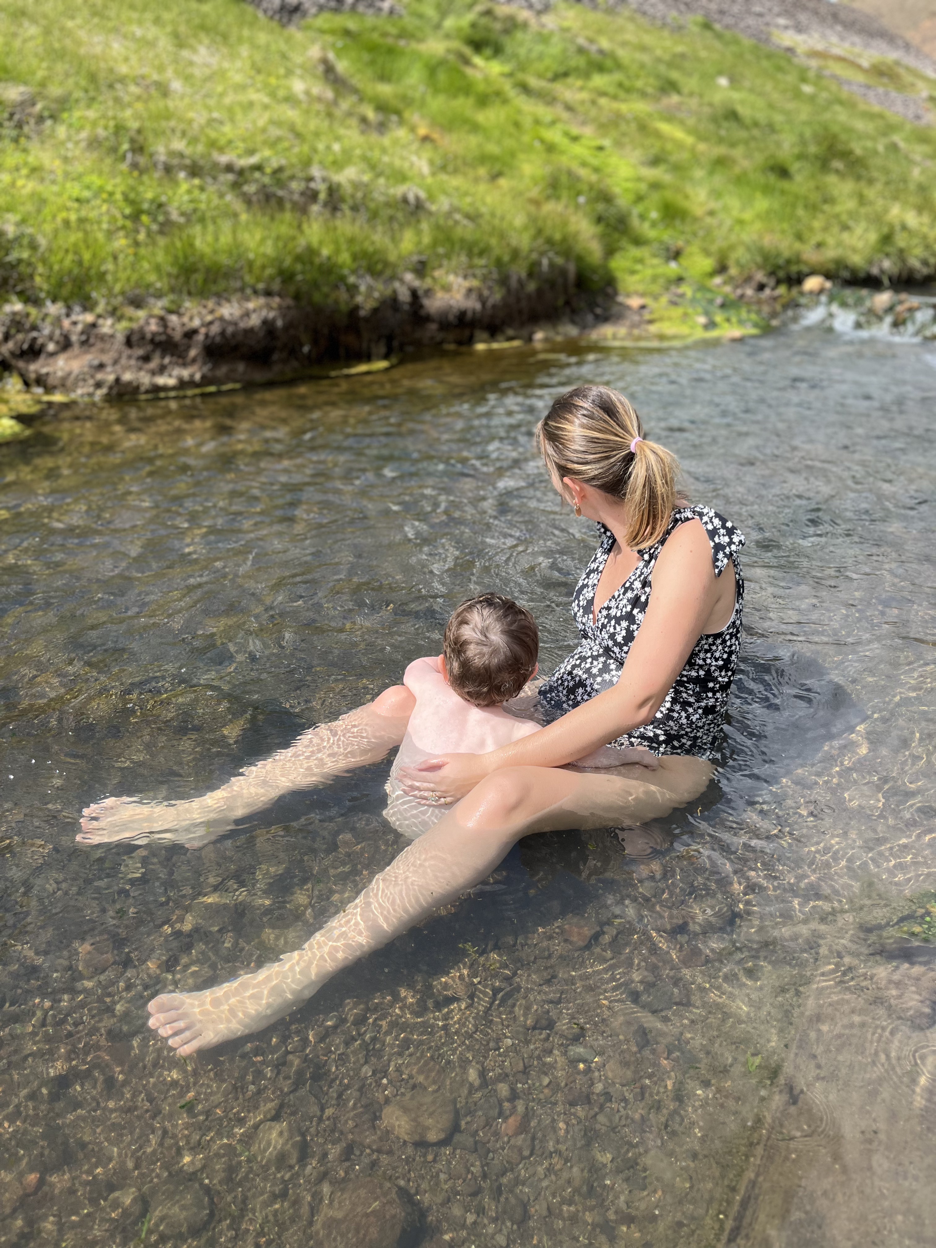 une femme et un bébé se baignent dans une rivière