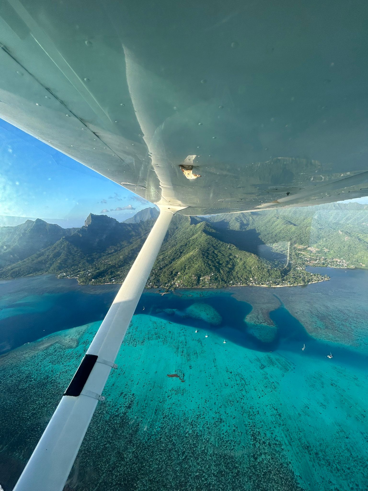 Les montagnes et le lagon de Moorea vue du ciel, et une aile d'avion